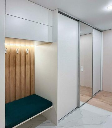 Белый шкаф-купе с подсветкой входной зоны, вид сбоку Встроенный шкаф-купе в прихожей